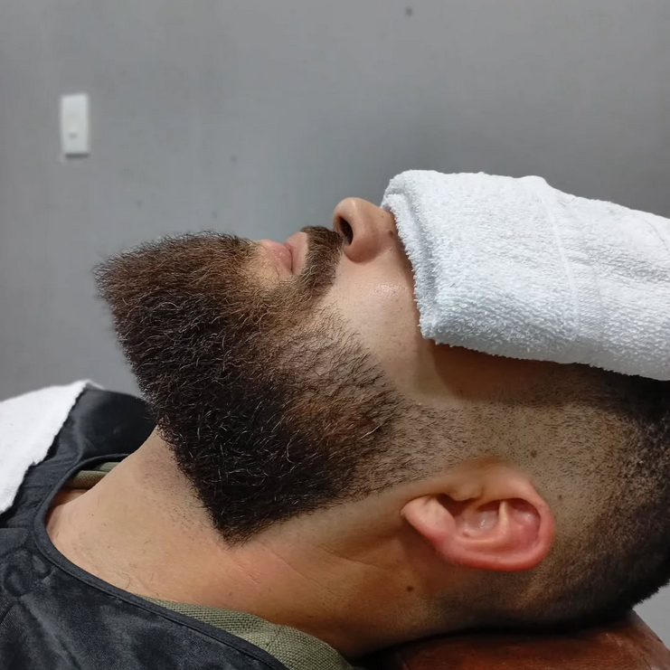 Barbeiro fazendo a barba do cliente